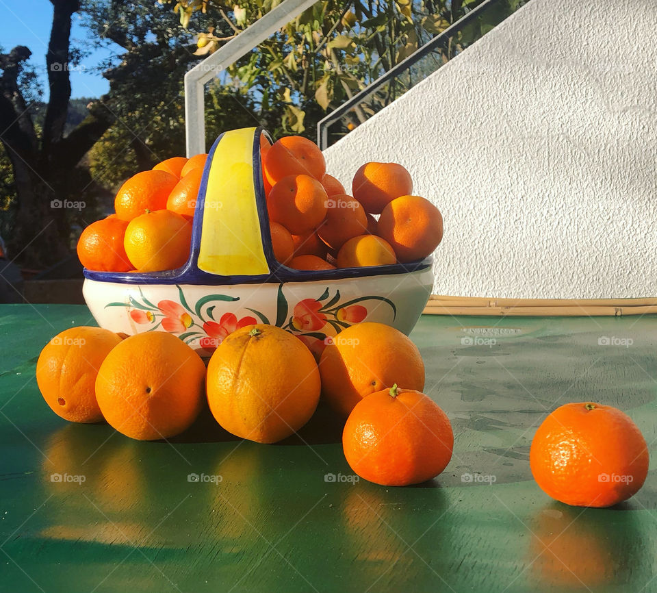 Fresh oranges in a fruit bowl placed on a green table