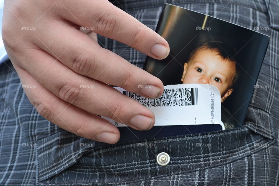 Man father parent with hand in back pocket which holds passport and photo of small male child son 