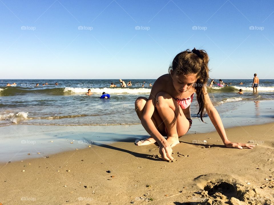 Girl on a beach writing on a sand
