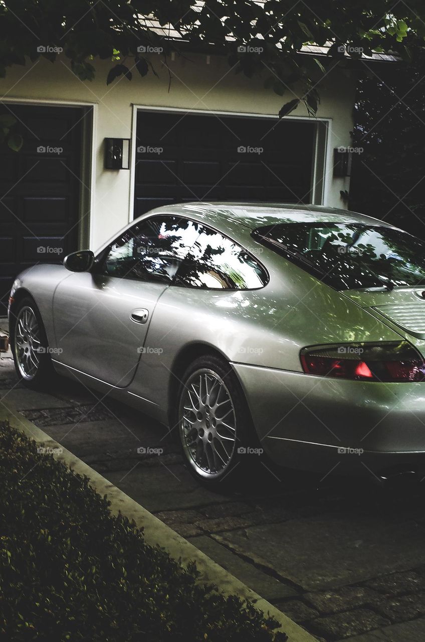 Beautiful vintage Porsche resting under a shade of trees