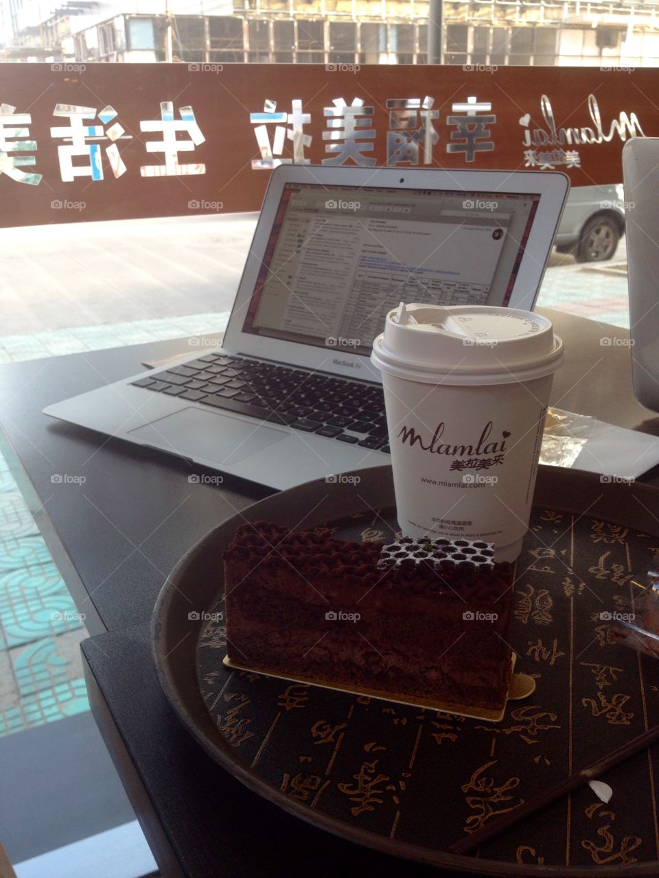 Morning coffee in a paper mug with a chocolate cake and a laptop 