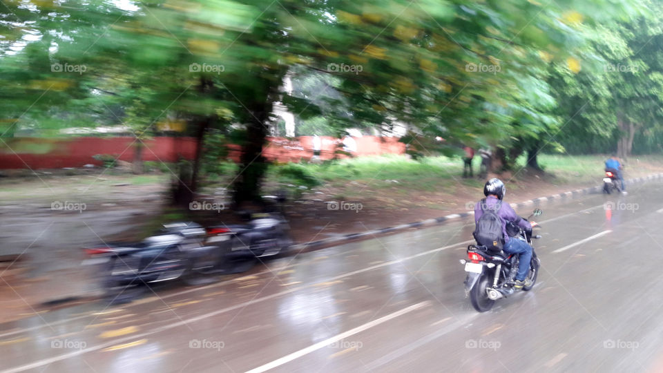 Rainy day, everything a blur except a motor bike rider.