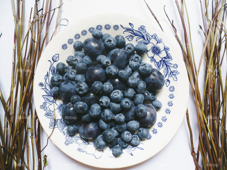 Berries of blueberries and plums on a white plate