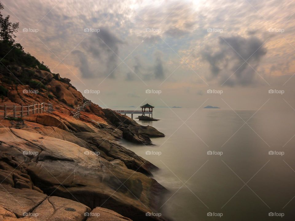 Cloudy sunrise at the coastline with the gazebo on the background. 