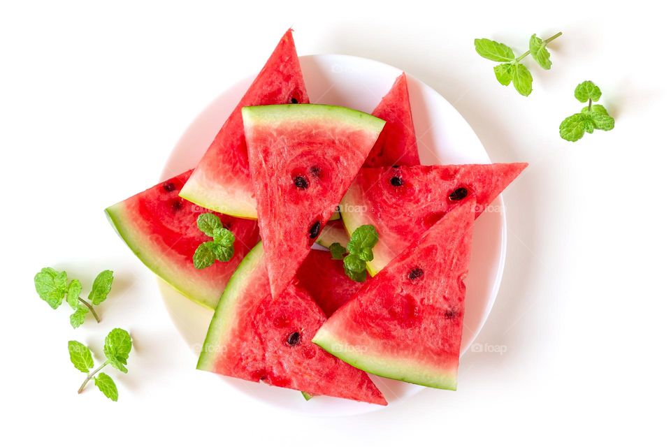 Slices of juicy watermelon with fresh mint leaves, delicious summer treats on a white plate 