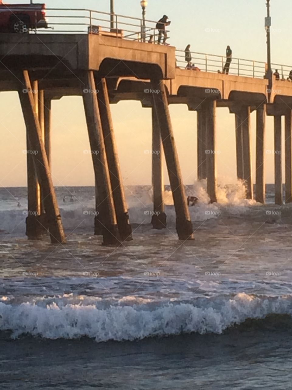 Challenging the pier. Surfer hallenging the pier at sunset