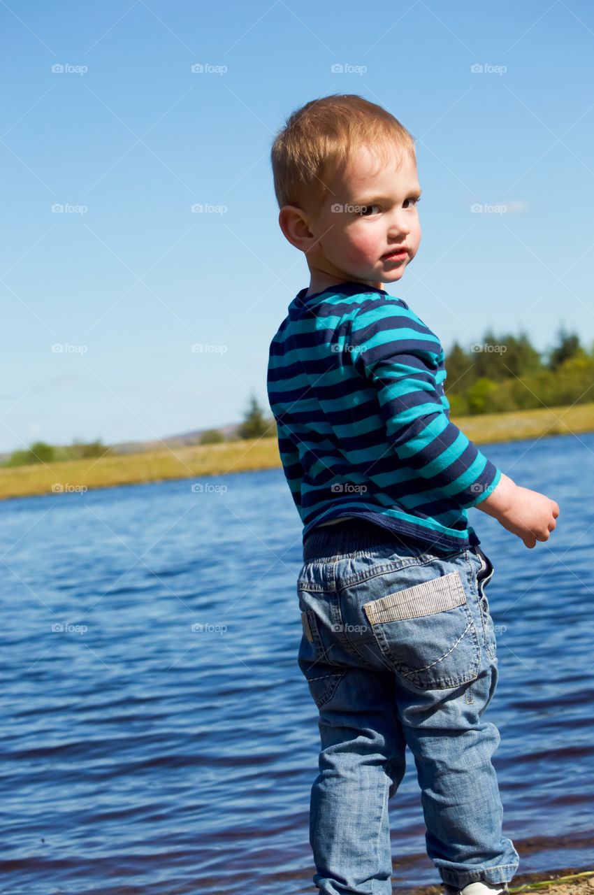 Little boy standing in front of lake