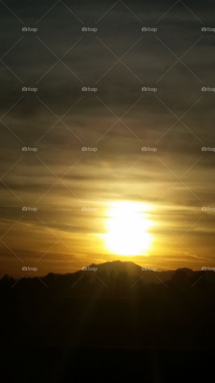 A MOUNTAINOUS BACKGROUND IN A GOLDEN SUNSET PICTURE. IS WORTH A THOUDAND AND ONE WORDS.  A BLENDED SKY WITH COLORS OH MY, HOW CAN ONE NOT, TAKE A DOUBLE LOOK, AND HOPE NOT GET THEIR NECK IN A KNOT.