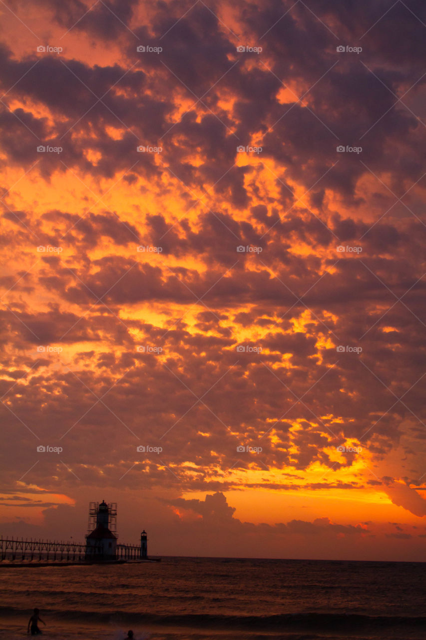 sunset on lake Michigan. a Sunset behind a lighthouse