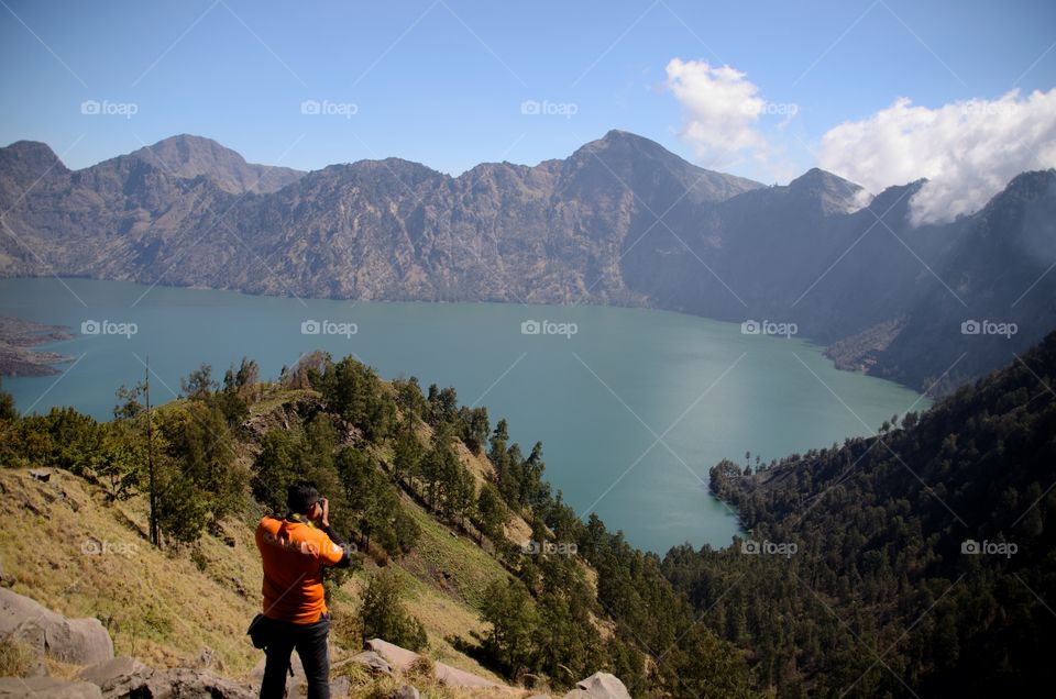 Beautiful nature background with unidentified hiker at Segara Anak Lake. Mount Rinjani is an active volcano in Lombok, indonesia. Soft focus due to long exposure.