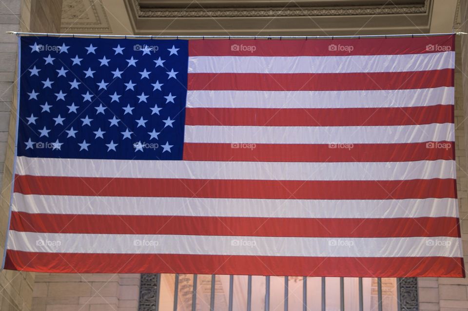 The American Flag hangs from the ceiling of a major USA commuter railroad station.