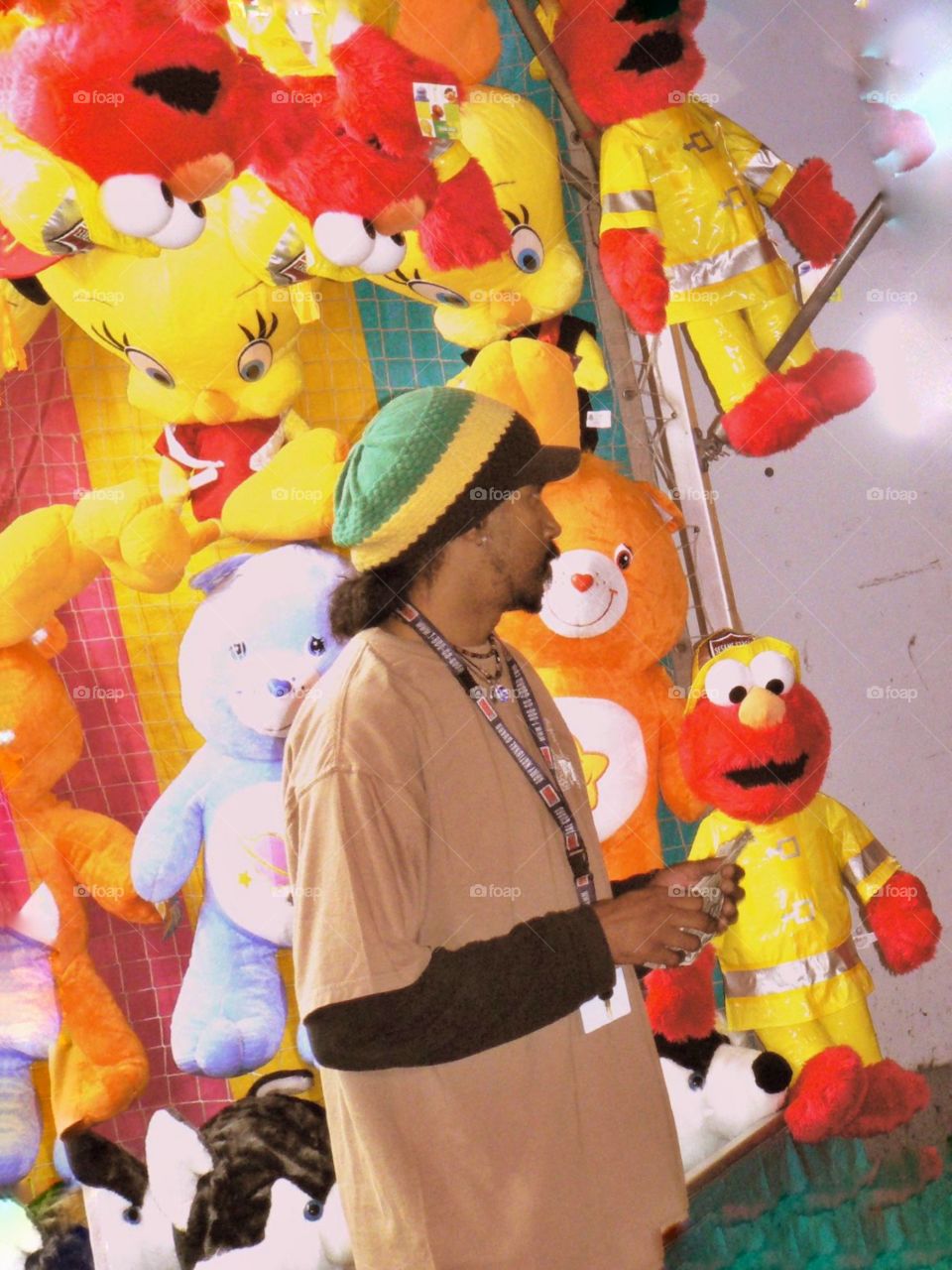 Rasta man on the midway . A colorful carnival worker and his prizes 