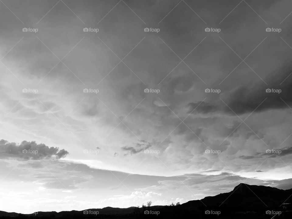 A black and white photo of mountains with clouds above them. 
