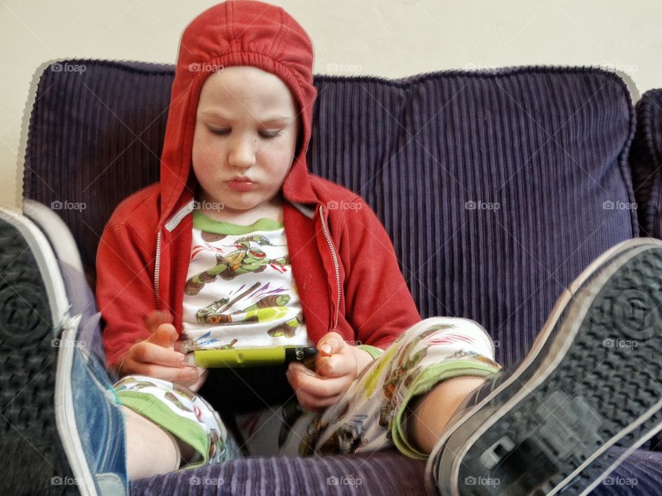 Child Playing With An Electronic Device
