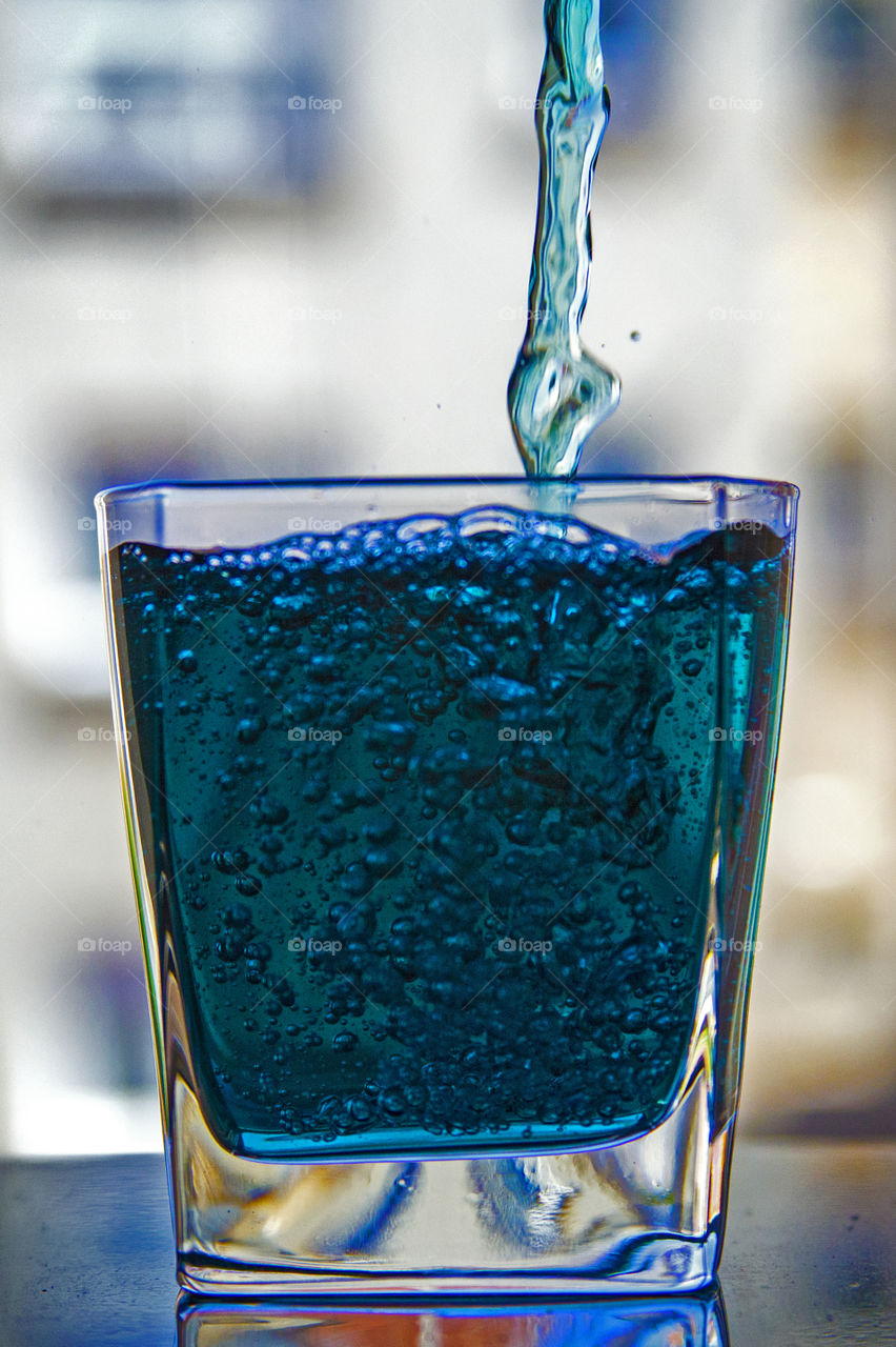 The glass with blue tea. The glass in which flows a trickle of blue Thai tea "Blue pea" and it bubbles form