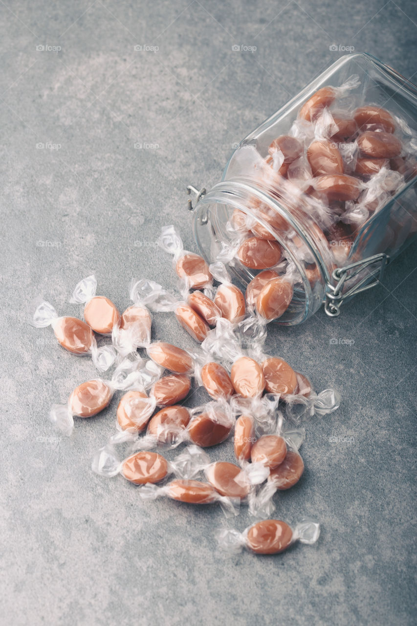 Jar filled with caramel milky candies on table