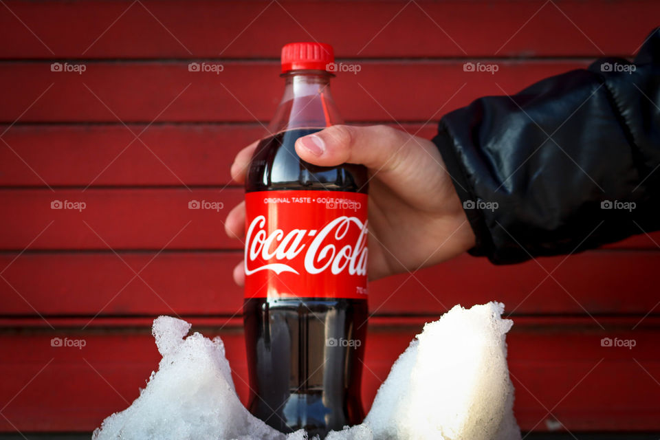 Man's hand holding a bottle of a Coca-Cola