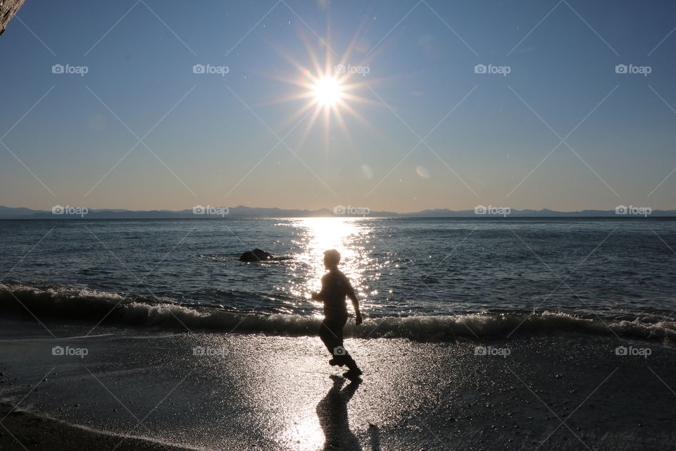 Silhouette of a Young man running on a sandy beach under the shining sun