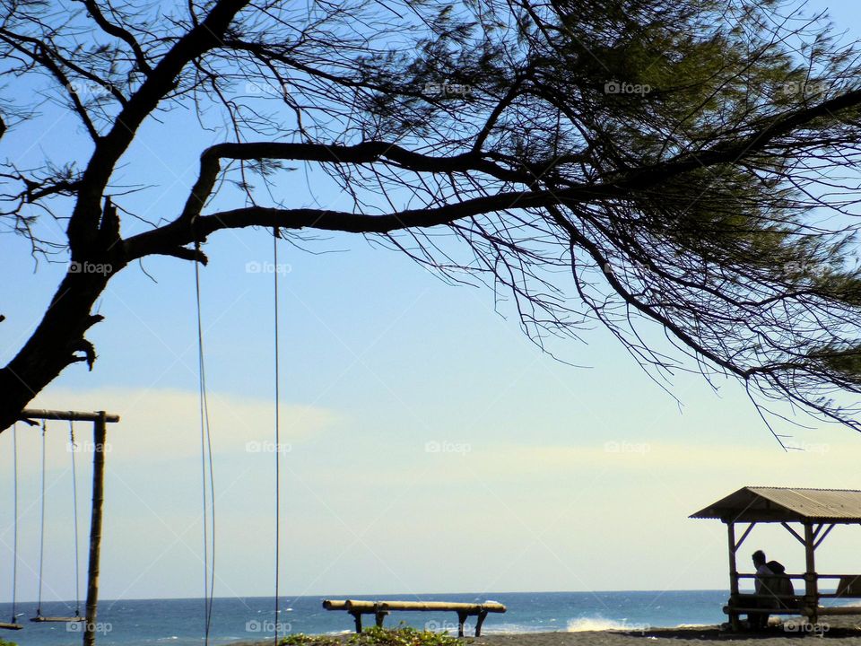 Shilouete huts and fir trees on the beach