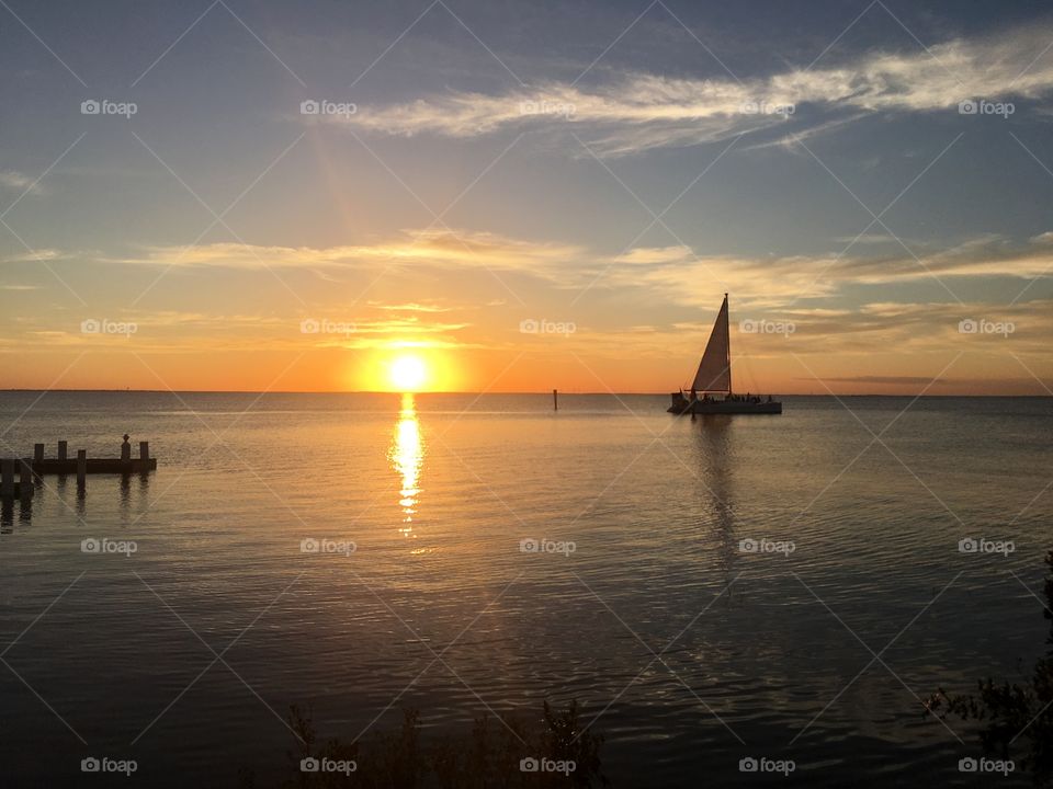 a sailboat in the sea during the sunset