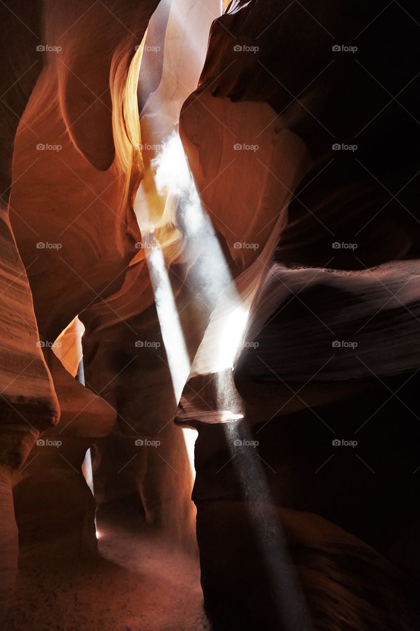 one ray of light seems like as a waterfall on the rocks of a canyon