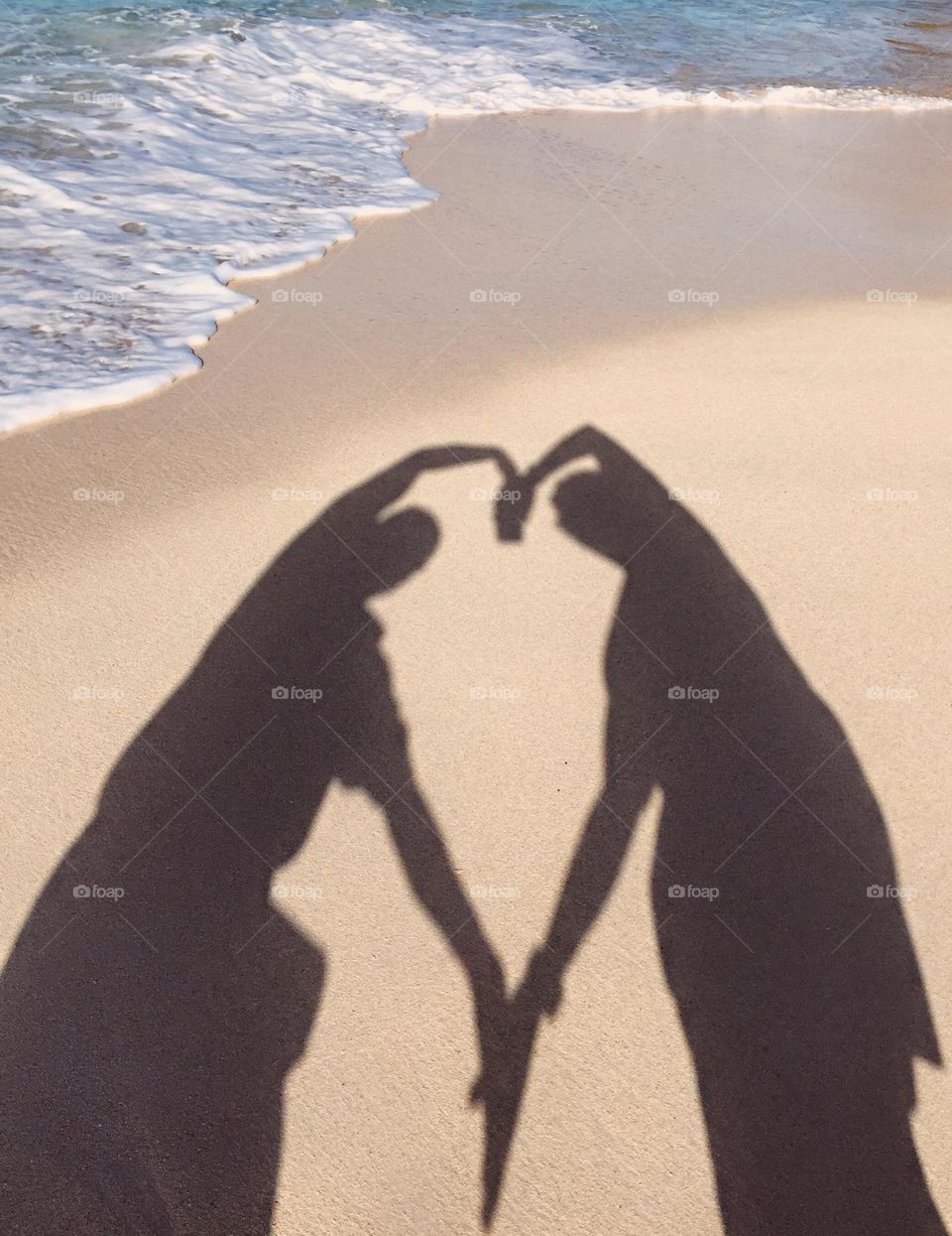 Couple on the beach making a heart with bodies, heart on the beach, sandy love 