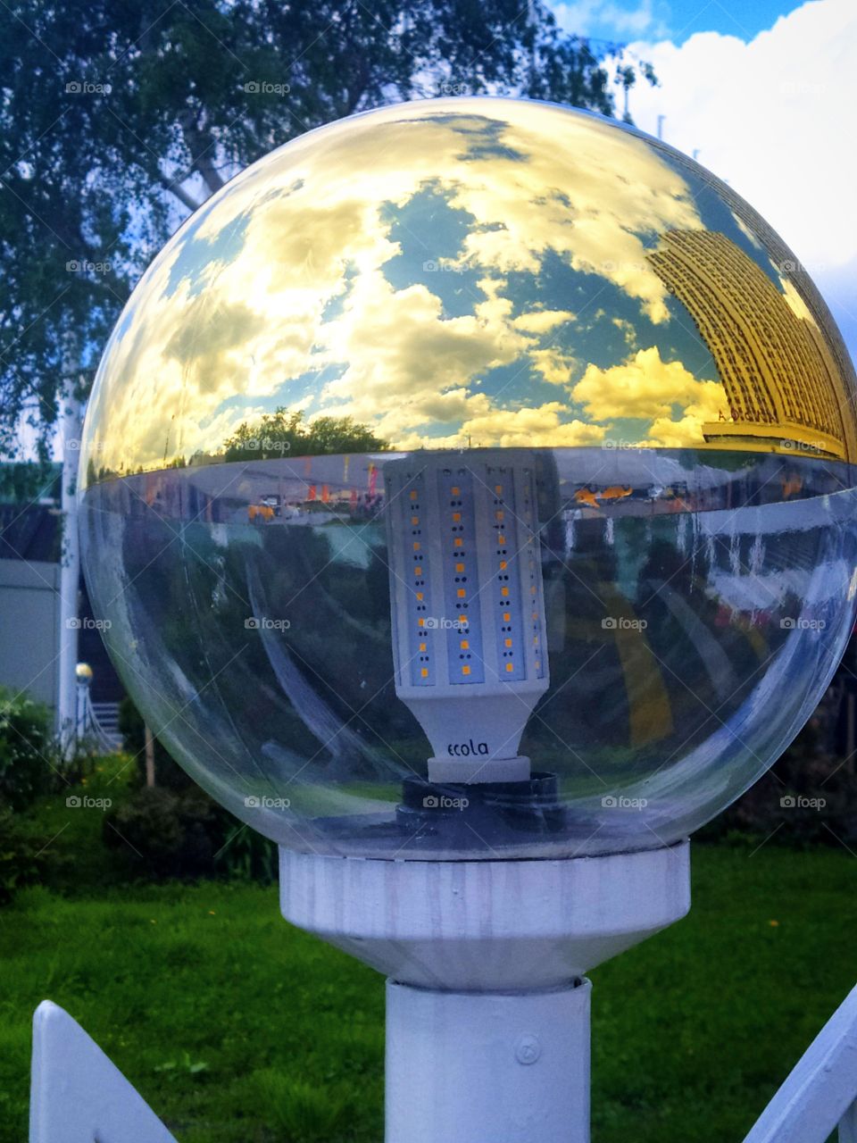 Street lamp, the upper part of which reflects all objects in sight: sky, clouds, buildings