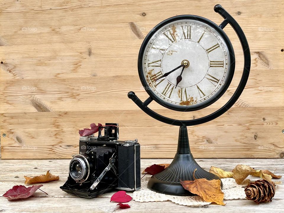 Retro watch with vintage camera on the wooden background 
