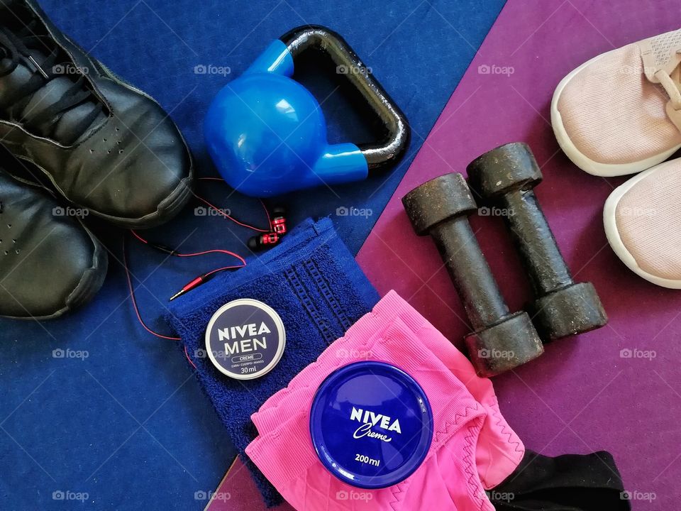 woman and man fitness theme flat lay. kettlebell, weights, towels and shoes and nivea creme
