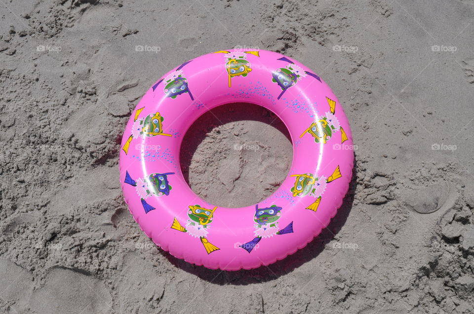 Pink pool float on the sand at the beach. 