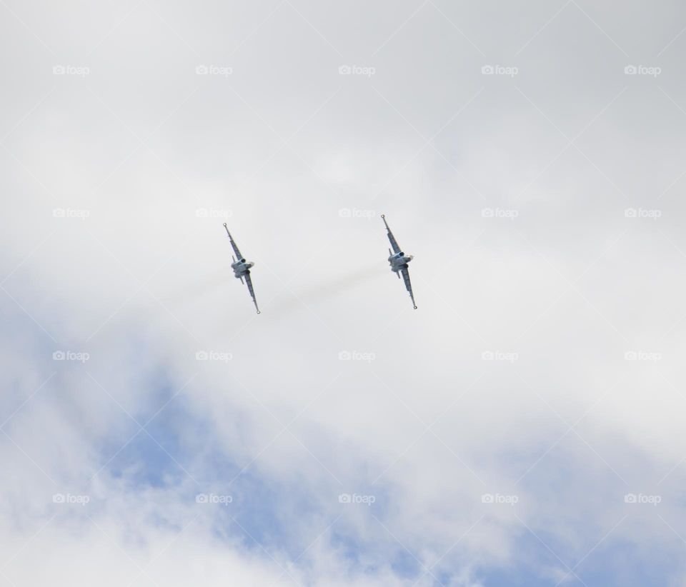 The plane is flying against the blue sky. Aerobatic figure, military aircraft.