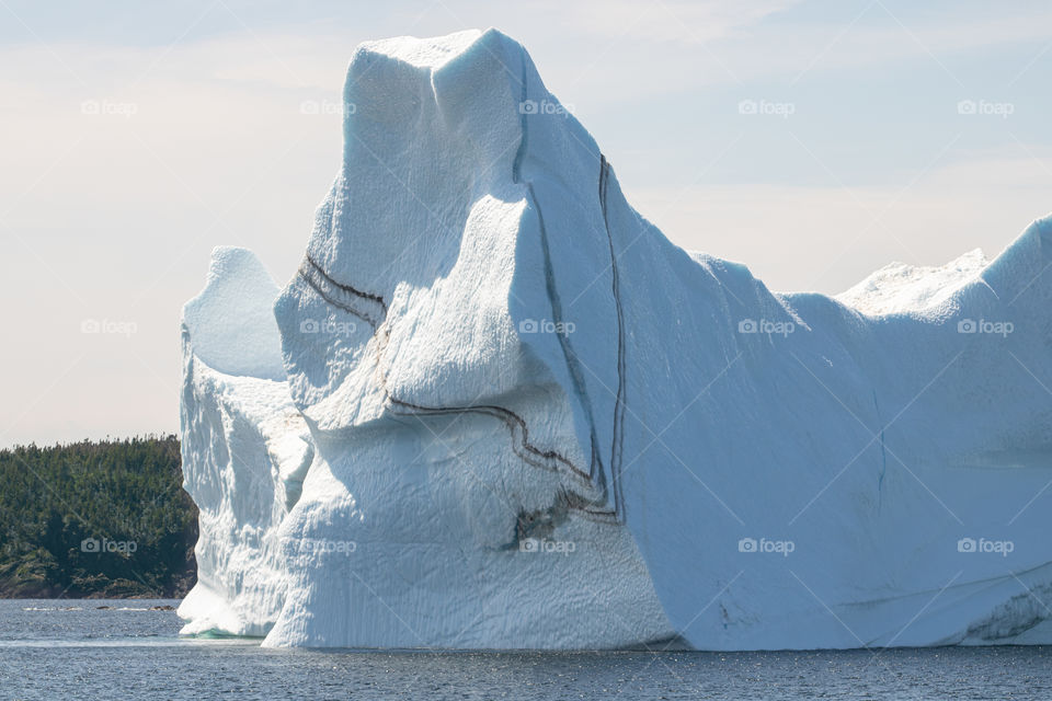 Huge iceberg with a stripe of sediment floating off the coast of Newfoundland, located in Iceberg Alley. 