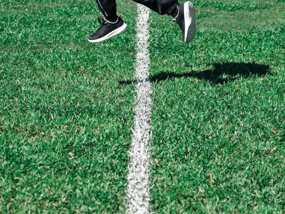 A girl jumping across a line on a field