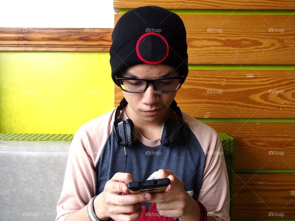 teenage boy wearing bonnet using a smartphone