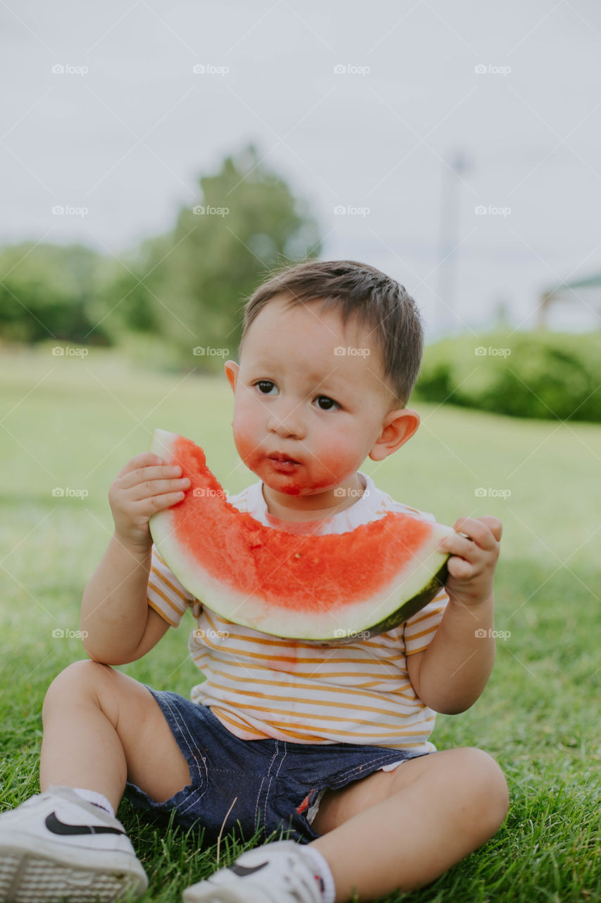 Boy eating watermelon at a park 