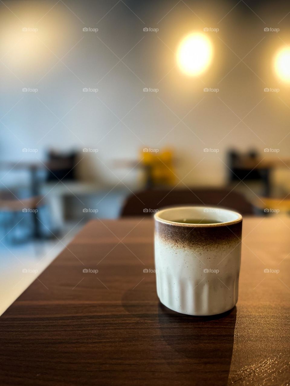 A cup of hot green tea on a wooden table in a small cafe