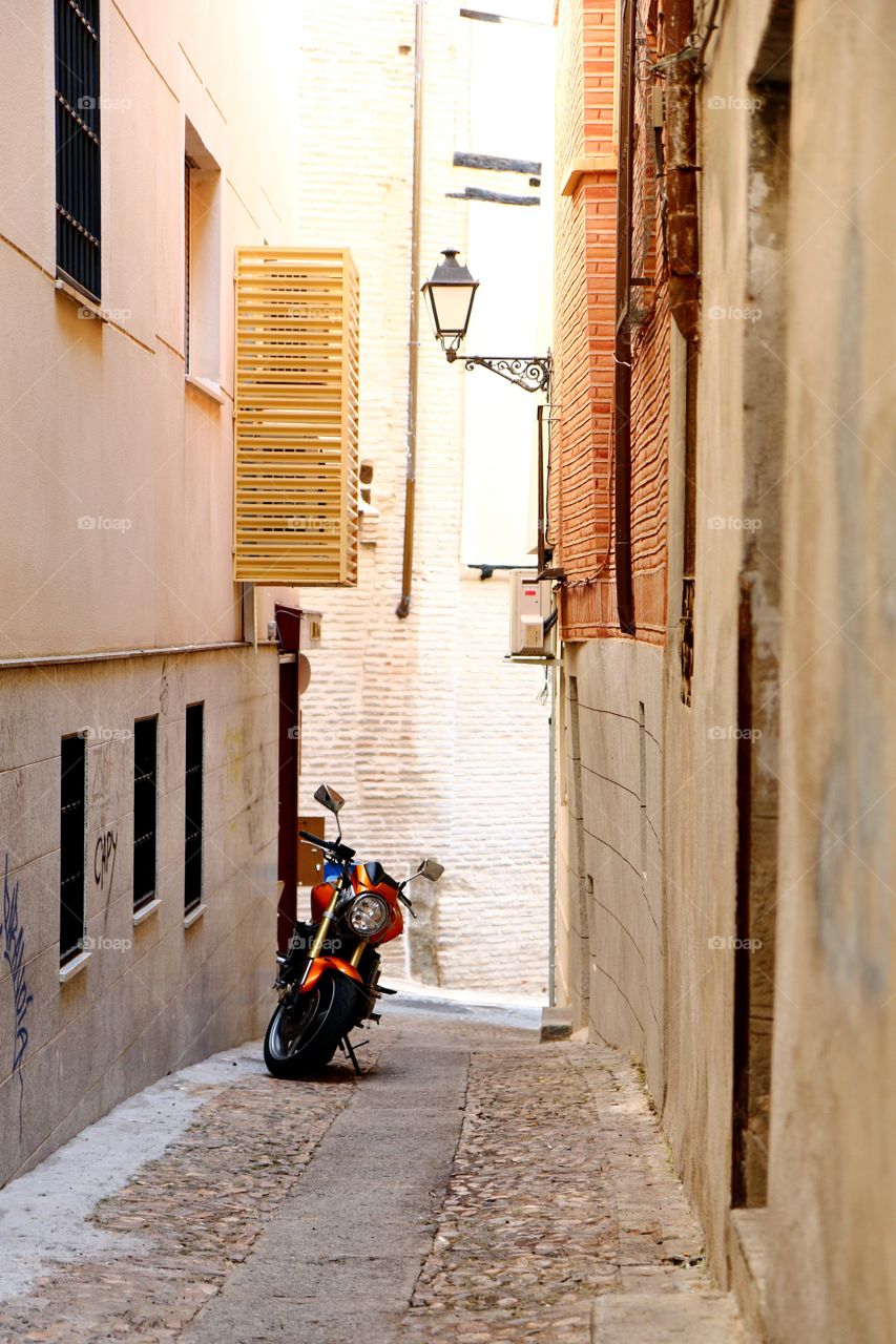 City environment . A motorcycle parked in a narrow street of Toledo, Spain 