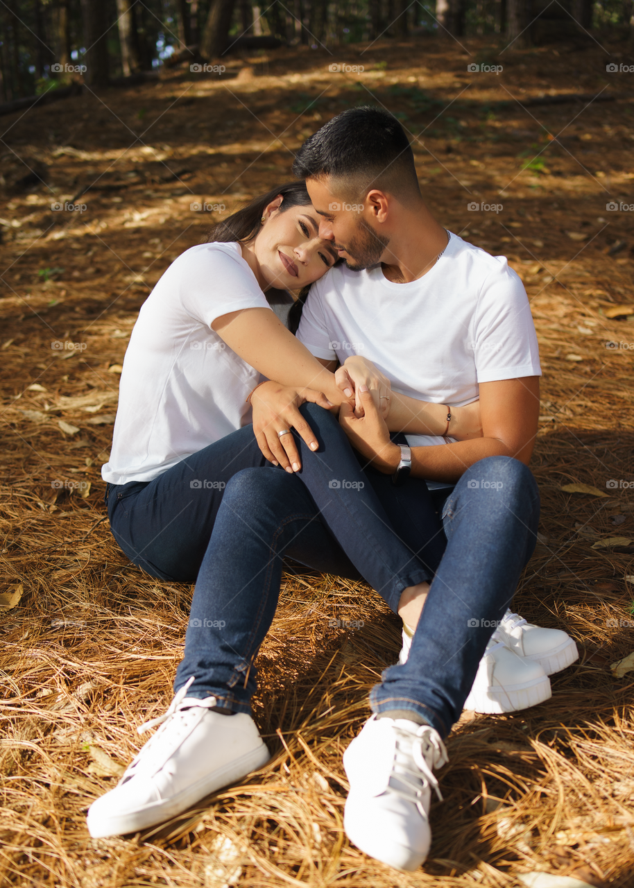 Couples of young people sitting in middle of the forest while looking falling in love, in a sunny day.