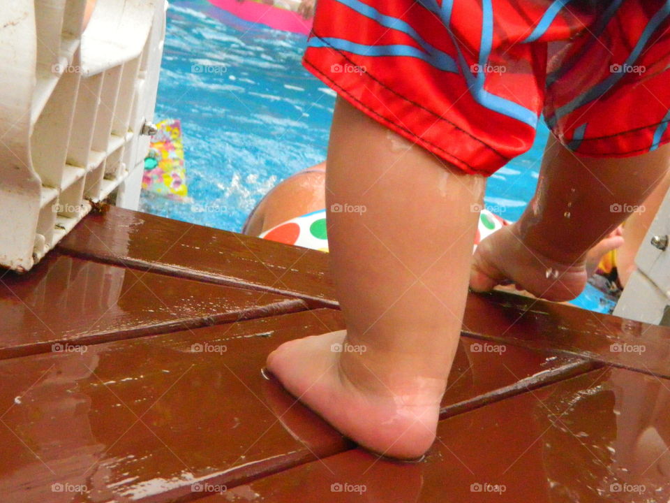Child feet on the edge of swimming-pool