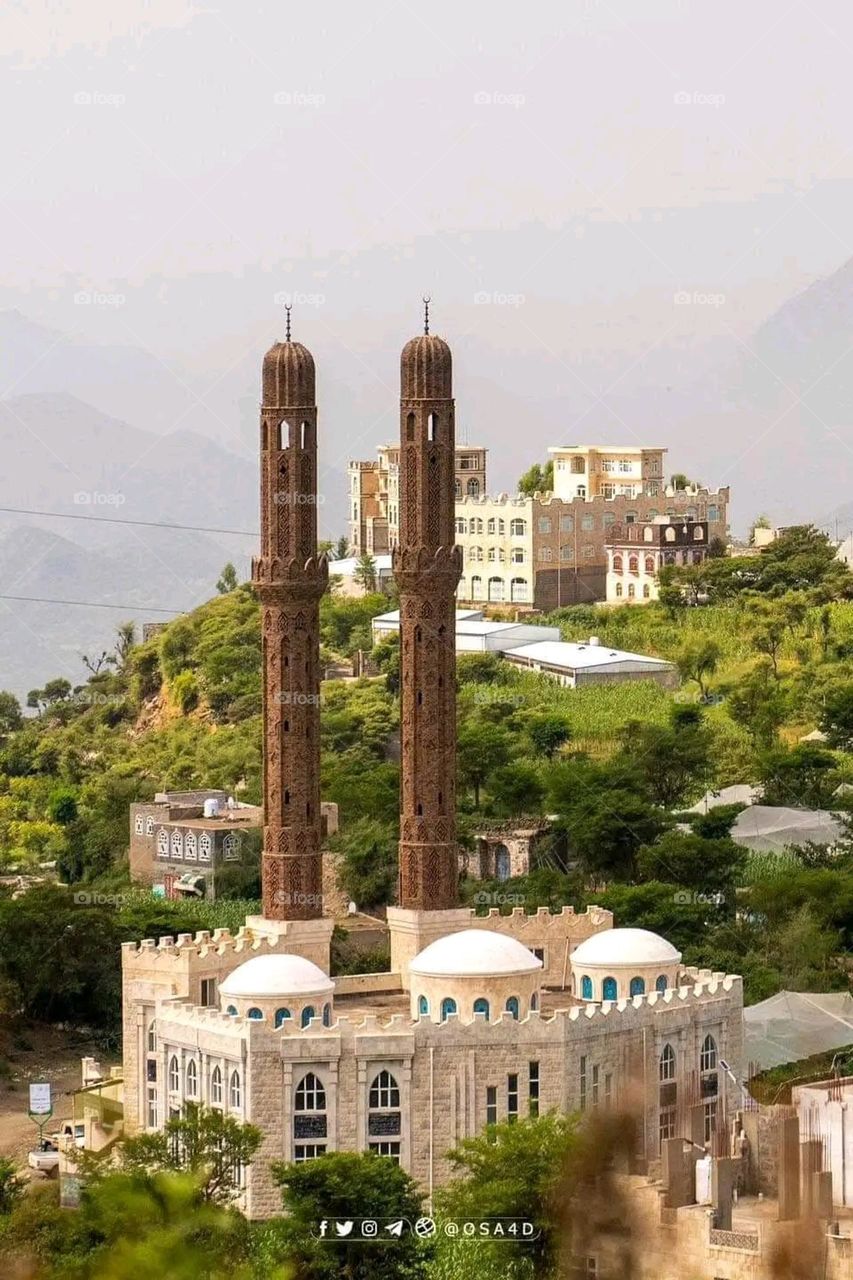 The image embodies a natural natural plate of the mountains of nature, where green agricultural stands are graded on the slopes as if they were lines of a poem, which fog harmoniously wrapped, and clouds hugged them in the mountain knife and the whis