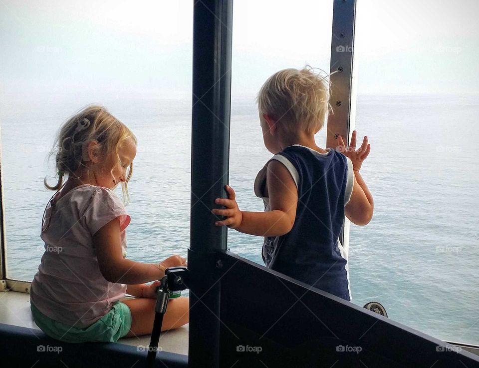 Two kids sitting in the window of a ferry