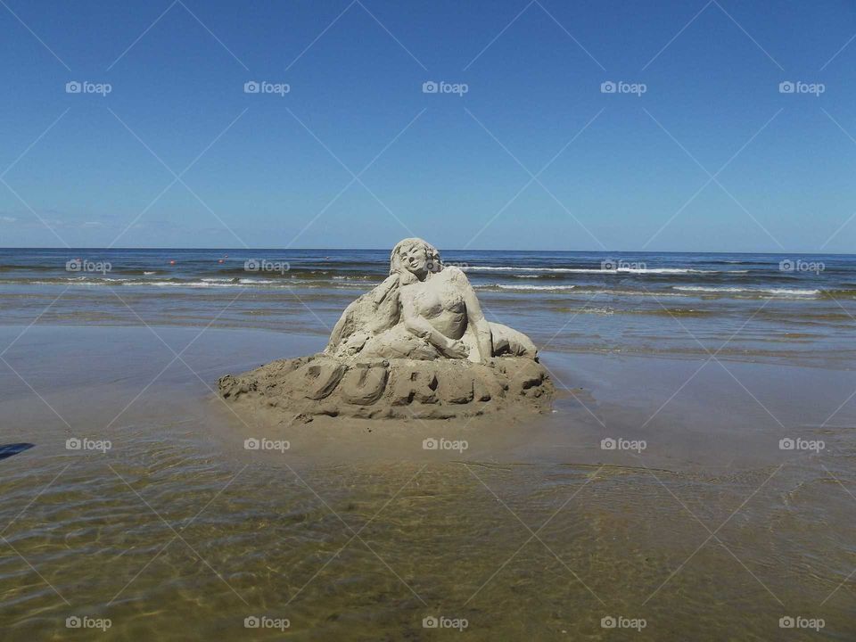 Mermaid sculpture out of the send on the beach un Jūrmala, Latvija