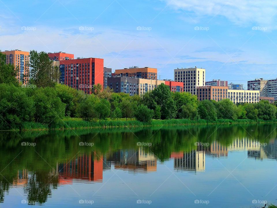 Green trees and colorful houses are reflected in the water.  Marvel