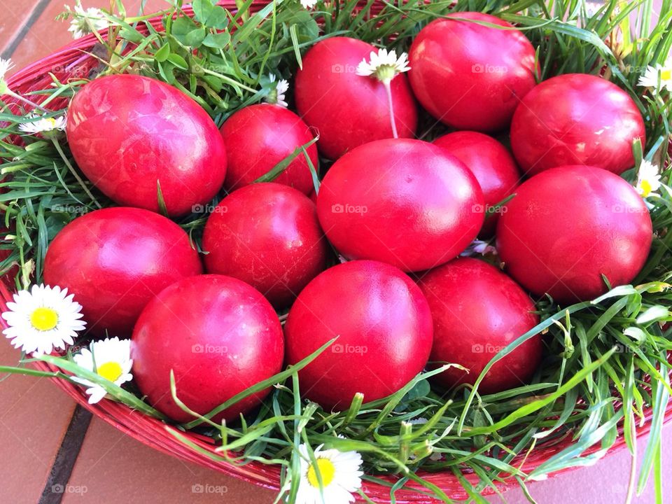 Red painted eggs in a basket with grass