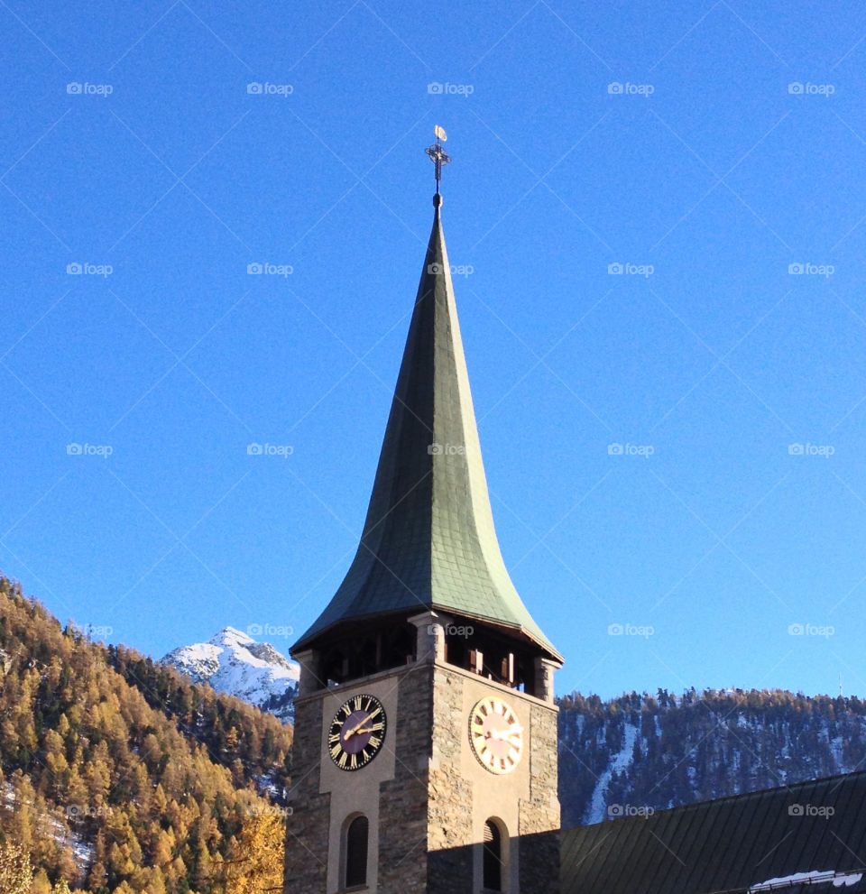 church tower in autumn with colours and snow zermatt by swisstraveler