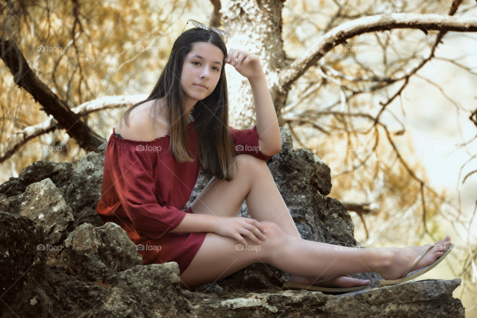 Pretty young woman sitting on rock