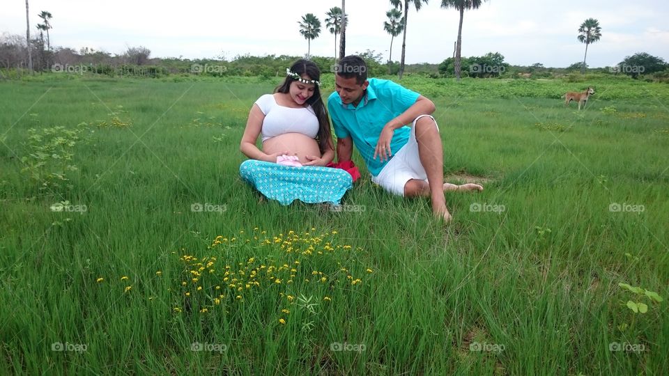 Pregnant woman sitting with her husband on grass