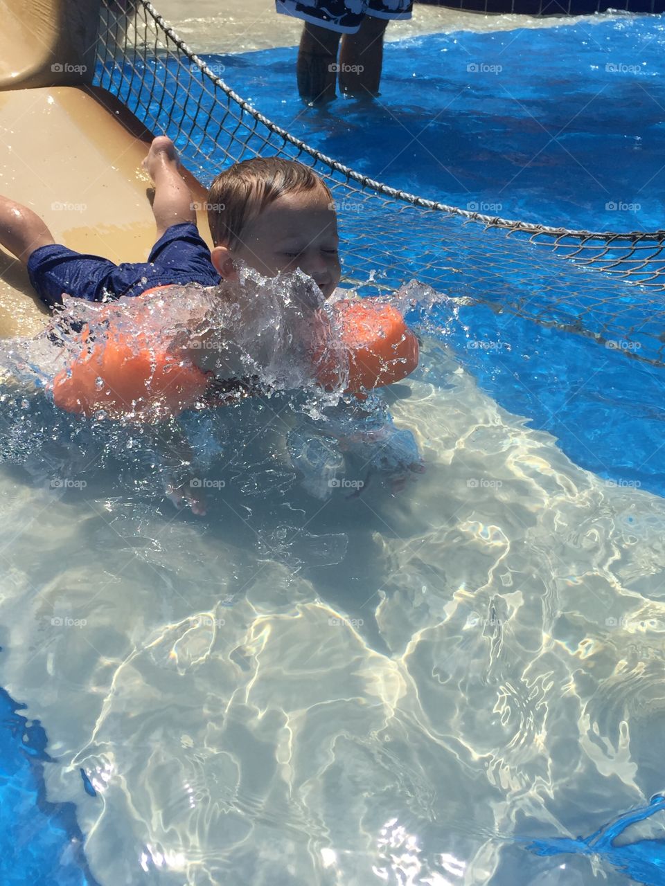 Little boy going head first down a water slide. 