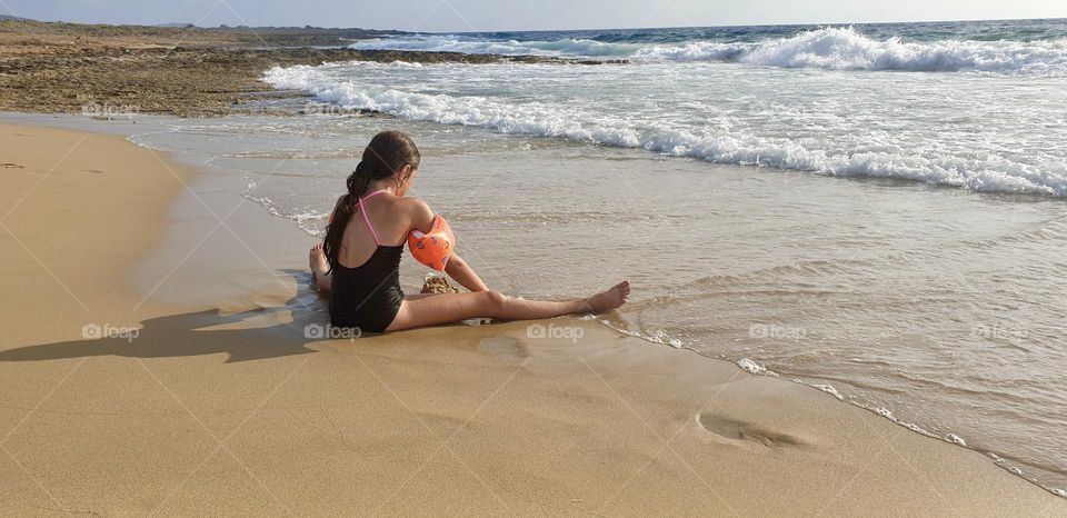 Girl playing with sand on the seashore