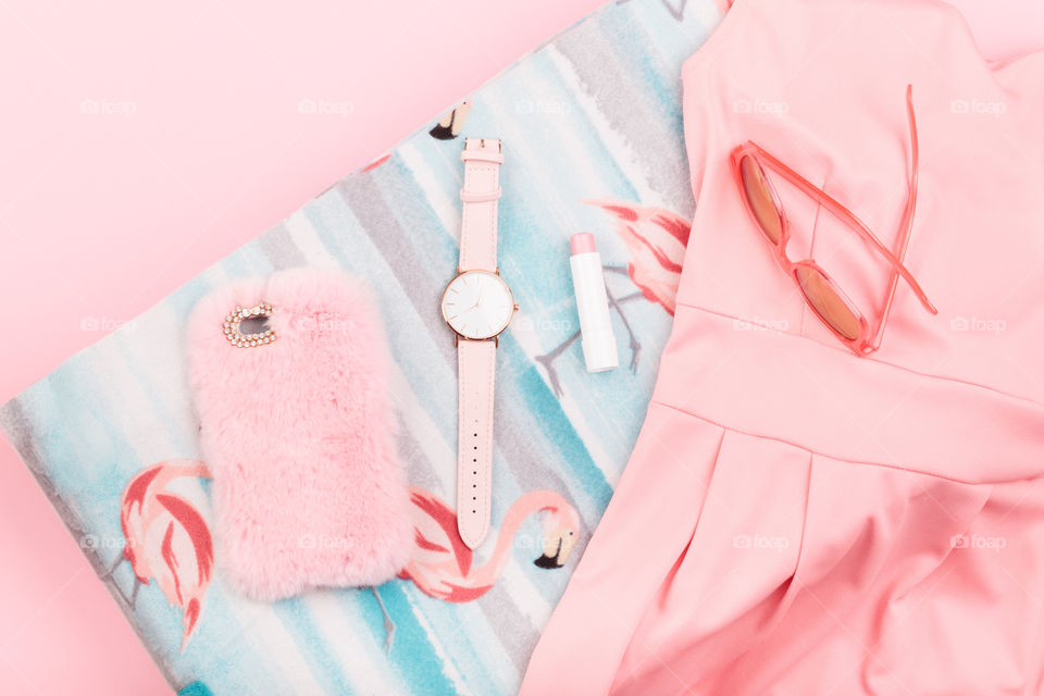 Female pink dress, mobile phone in pink case, watch with pink stripe on pink background